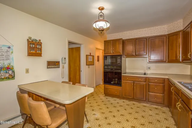 a kitchen with stainless steel appliances granite countertop a sink a stove a refrigerator cabinets and chairs