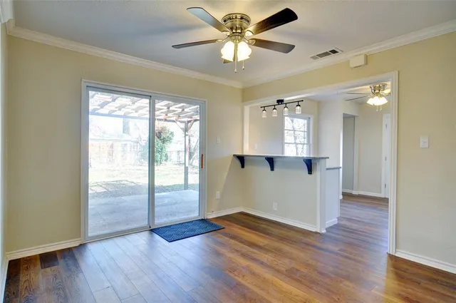 a view of an empty room with window and wooden floor