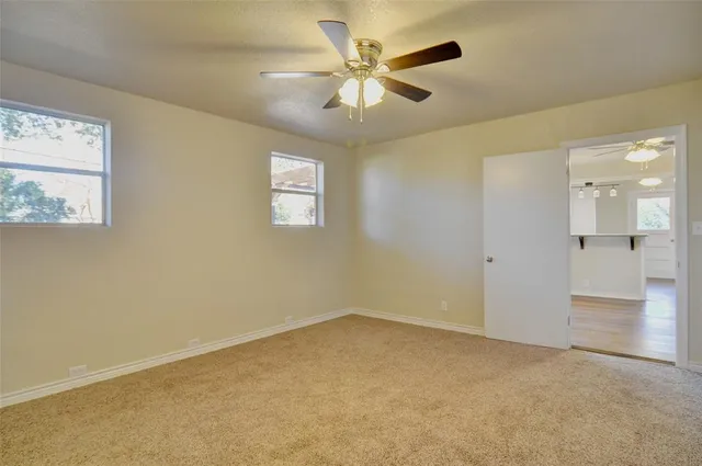 an empty room with windows and fan