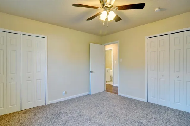 a view of an empty room and chandelier fan