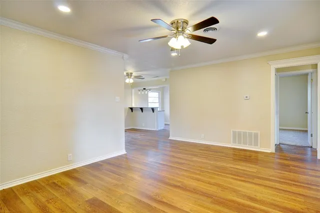 an empty room with wooden floor and a ceiling fan