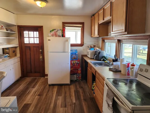 a kitchen with a refrigerator a stove top oven a sink and dishwasher with wooden floor