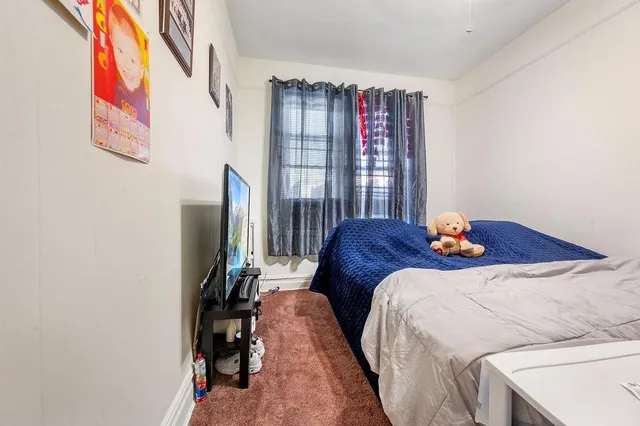 a bed sitting in a bedroom next to a window with pc on it