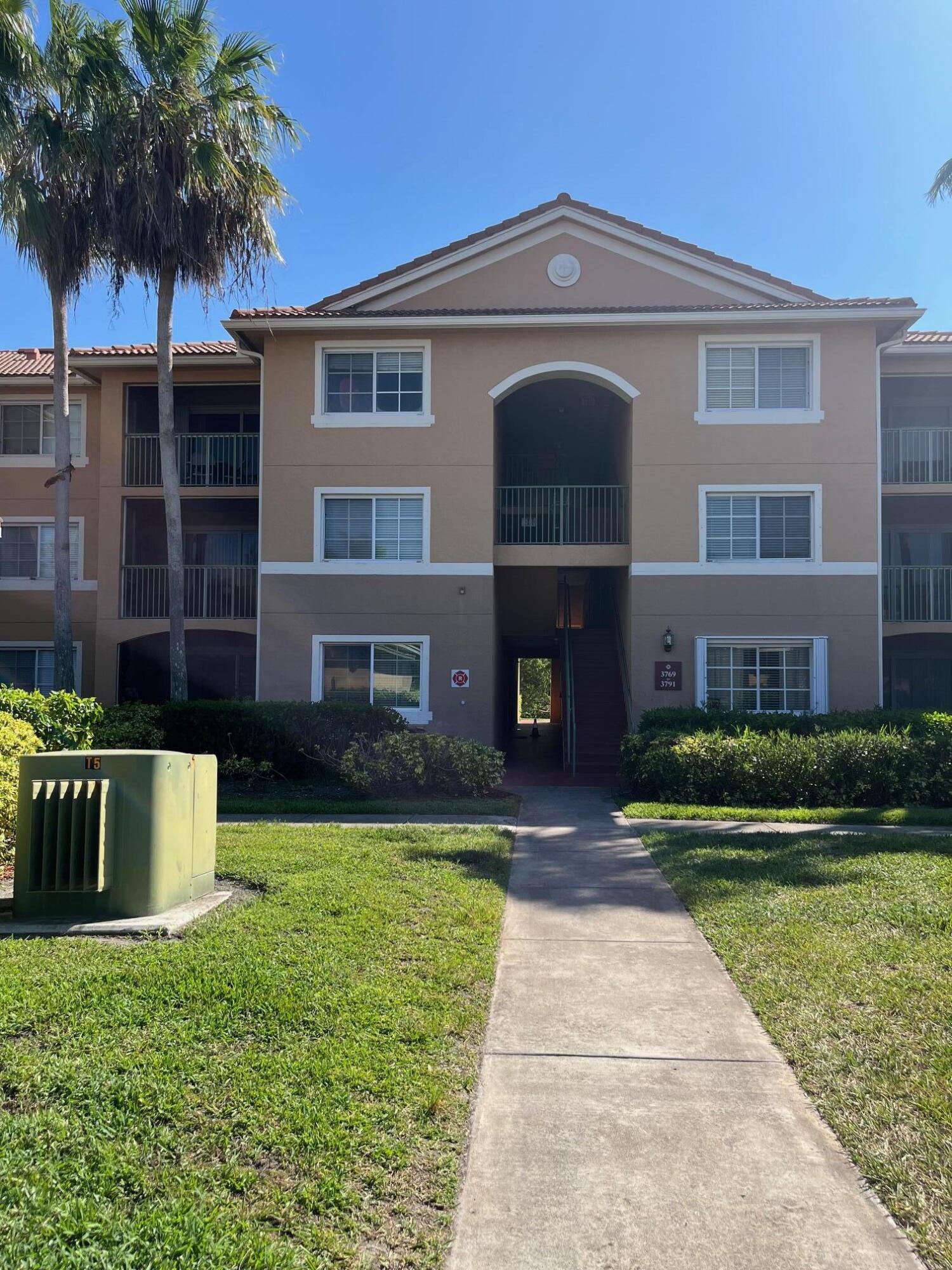 3769 Northwest Mediterranean Lane, Unit 2308 Jensen Beach, FL 34957 - Photo 1 of 16 a front view of a house with a garden and yard