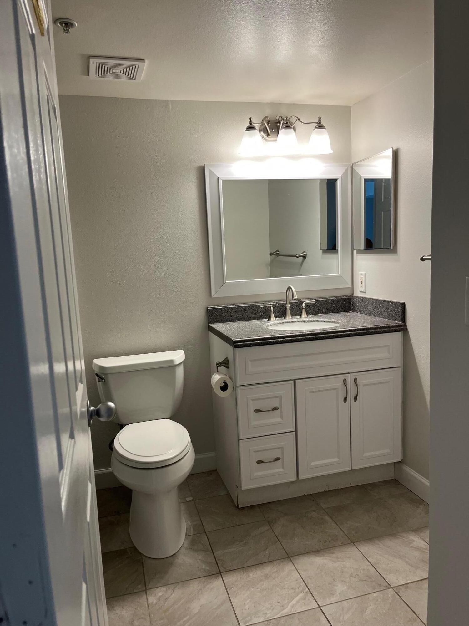 3769 Northwest Mediterranean Lane, Unit 2308 Jensen Beach, FL 34957 - Photo 11 of 16 a bathroom with a toilet sink and mirror