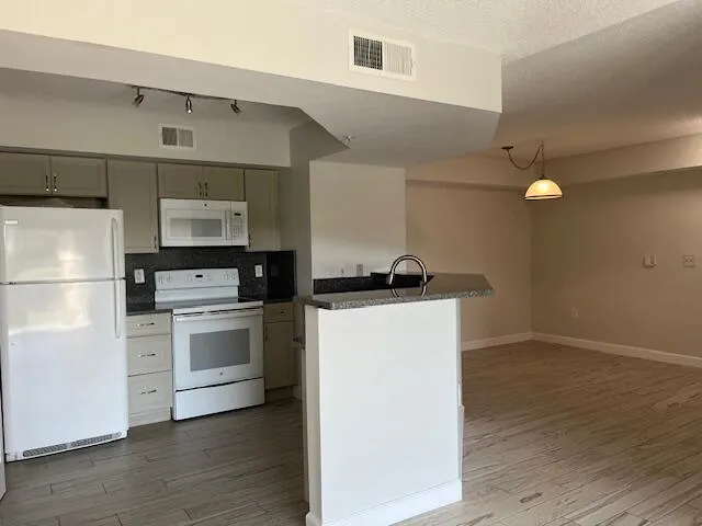a kitchen with cabinets stainless steel appliances and wooden floor
