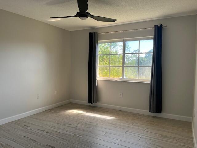3769 Northwest Mediterranean Lane, Unit 2308 Jensen Beach, FL 34957 - Photo 10 of 16 an empty room with wooden floor chandelier and windows