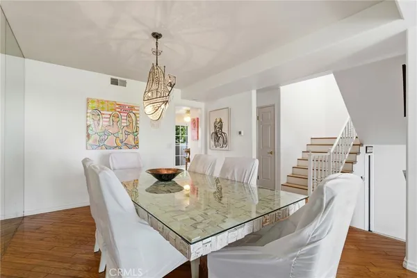 a dining room with wooden floor a chandelier a wooden table and chairs