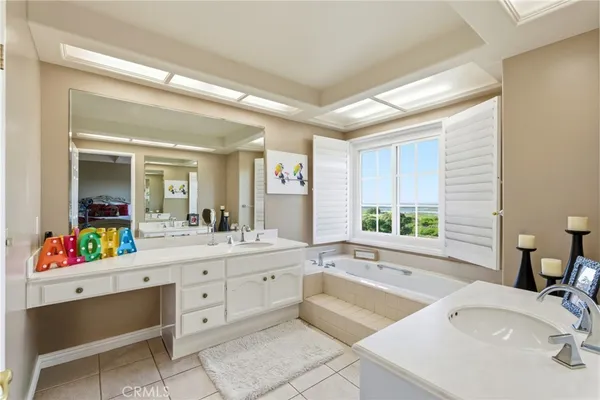 a bathroom with a double vanity sink bathtub and next to a window
