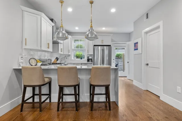 a kitchen with stainless steel appliances granite countertop a dining table chairs and white cabinets