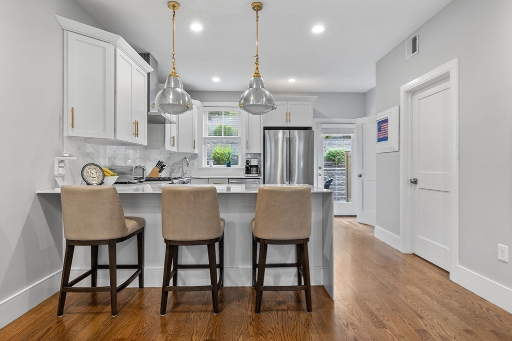 579 Baker Street, Unit 579 Boston, MA 02132 - Photo 2 of 30 a kitchen with stainless steel appliances granite countertop a dining table chairs and white cabinets