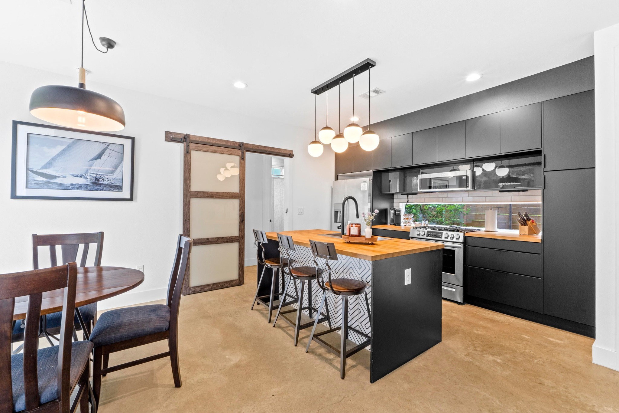 1706 Perez Street, Unit 2 Austin, TX 78721 - Photo 7 of 29 A chic kitchen features dark cabinetry, a spacious island with seating, and a sleek dining area.