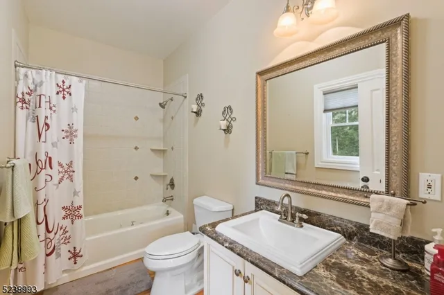a bathroom with a granite countertop sink a toilet a mirror a bathtub and shower