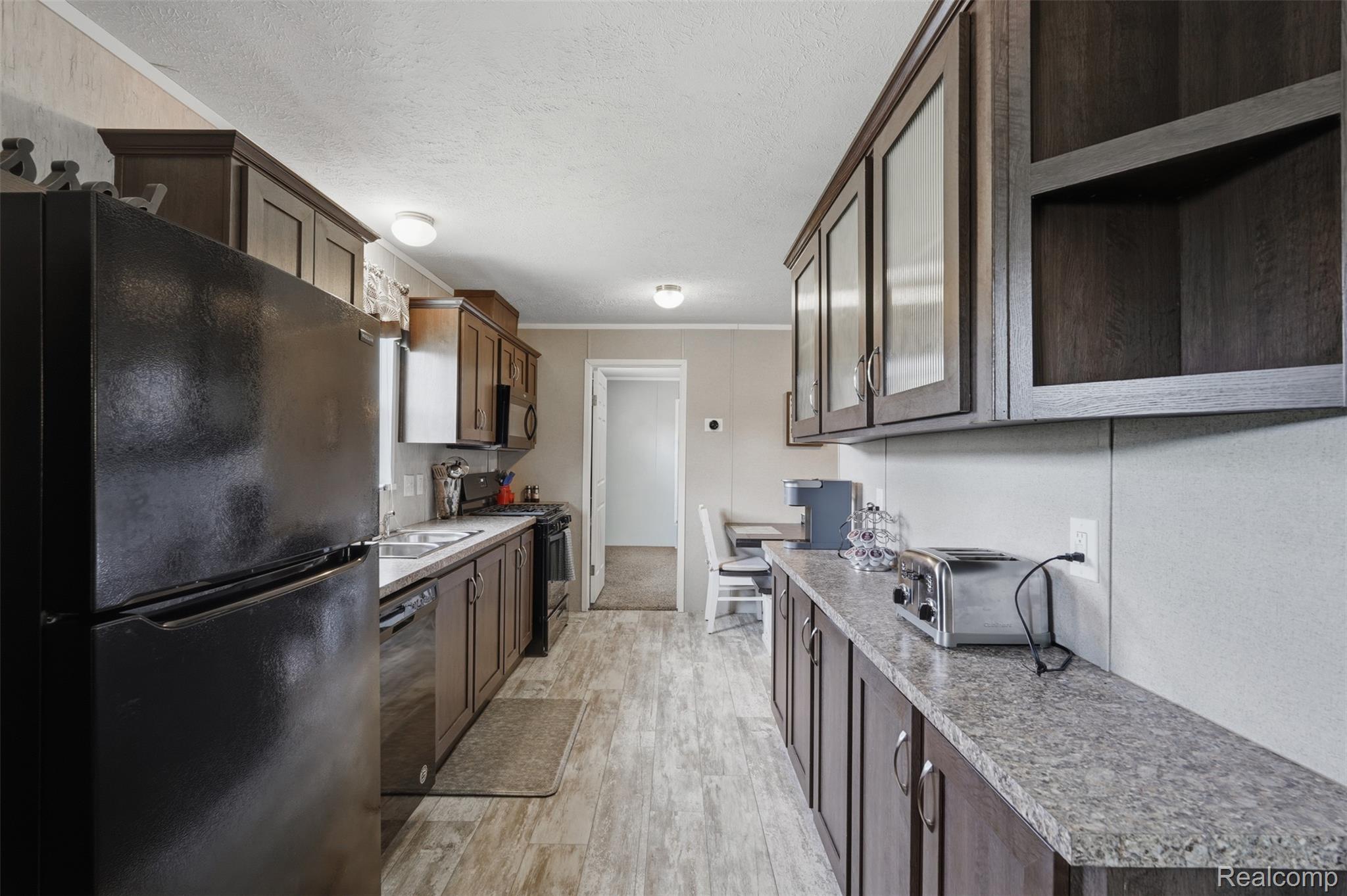 92 Normandy Drive Howell, MI 48843 - Photo 7 of 24 Galley kitchen featuring wood-finish cabinetry, a black appliance suite, and light-toned countertops
