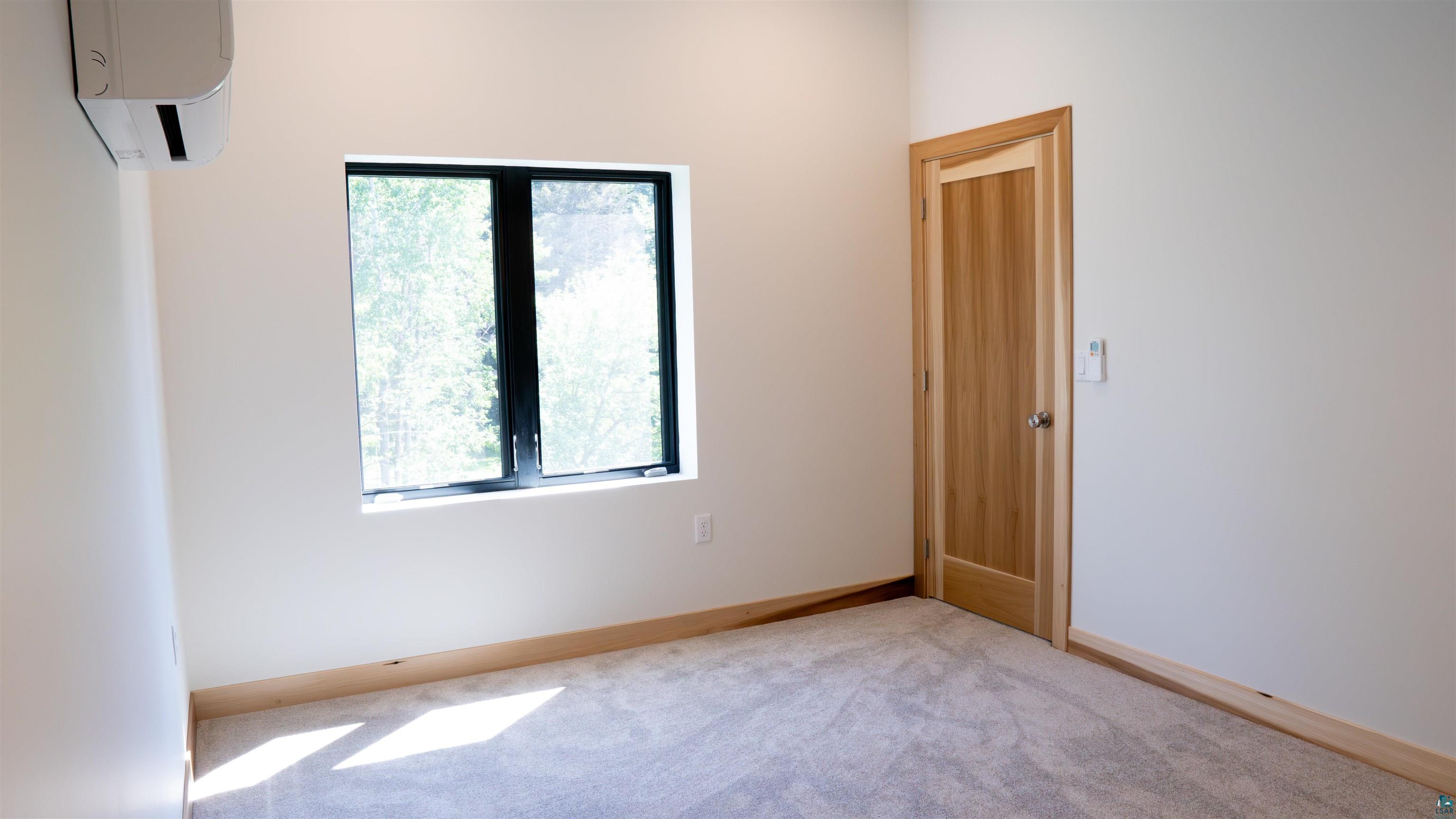89180 Meadow Trail Cornucopia, WI 54827 - Photo 19 of 26 Carpeted empty room with a wall unit AC and a wealth of natural light