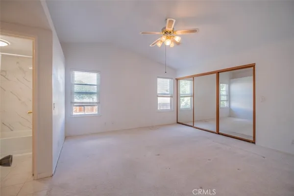 an empty room with windows and chandelier fan