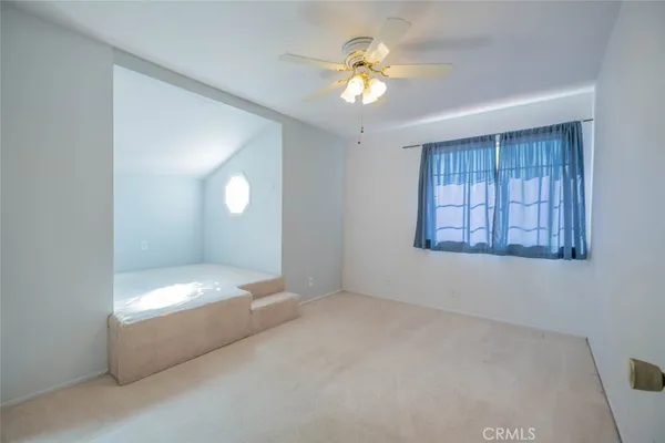 an empty room with windows and chandelier fan