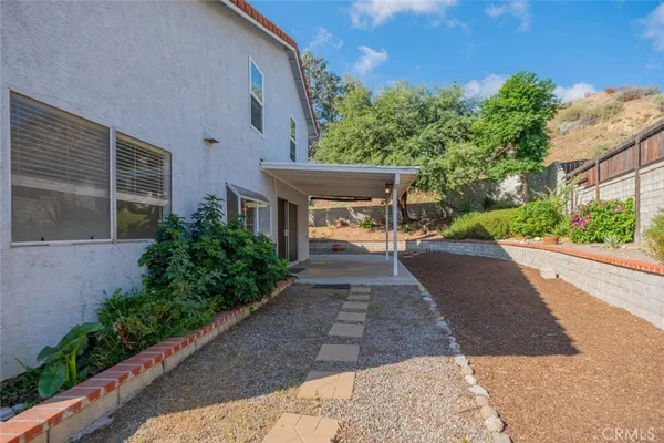 a view of a patio with plants and trees with wooden fence