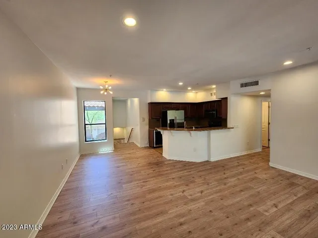 a view of a big room with wooden floor and a kitchen