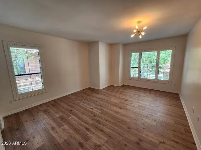 an empty room with wooden floor chandelier and window
