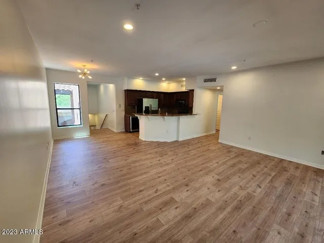 a view of a big room with wooden floor and kitchen view