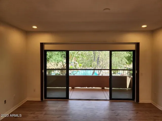 a view of empty room with wooden floor and fan
