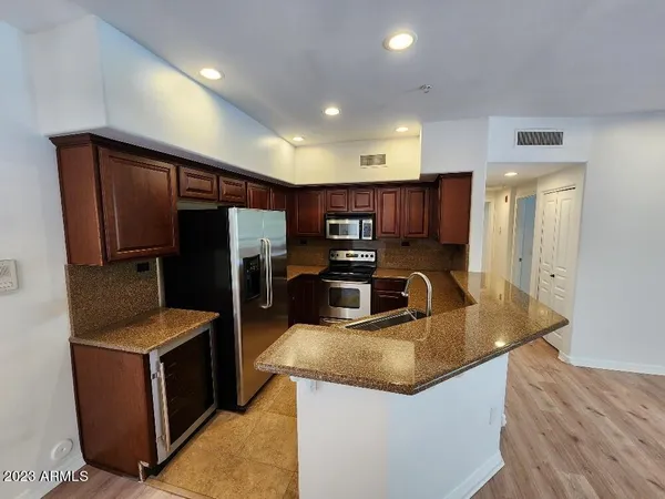 a kitchen with stainless steel appliances granite countertop a refrigerator a sink and a stove