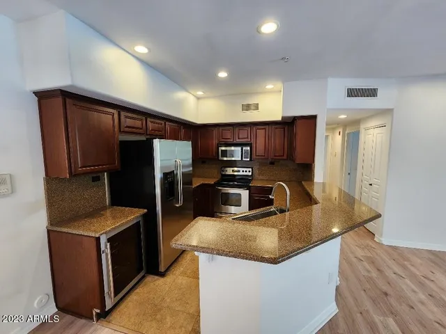 a kitchen with stainless steel appliances granite countertop a refrigerator a sink and a stove