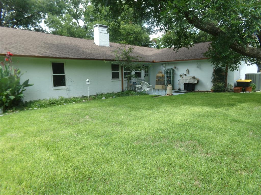 5110 Wedgefield Road Granbury, TX 76049 - Photo 21 of 23 Expansive green lawn bordering the property, featuring a white stucco exterior with a brown shingle roof, multiple windows, and a white chimney