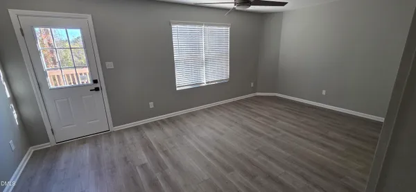 an empty room with wooden floor and windows