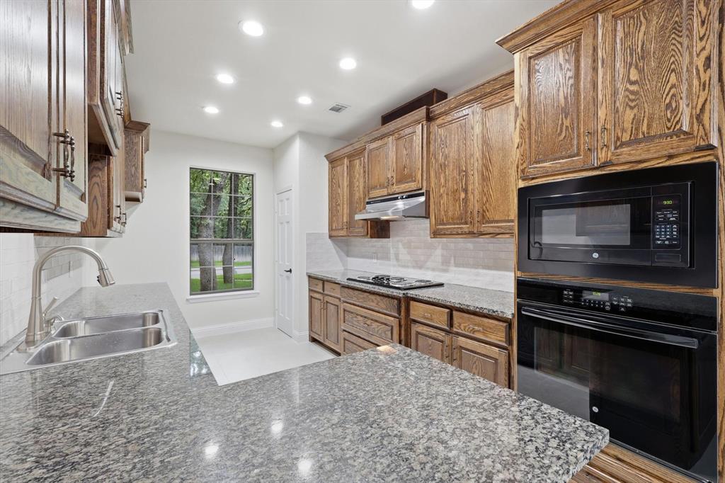19 Timbergreen Circle Denton, TX 76205 - Photo 12 of 40 a kitchen with stainless steel appliances granite countertop a stove a sink and a microwave