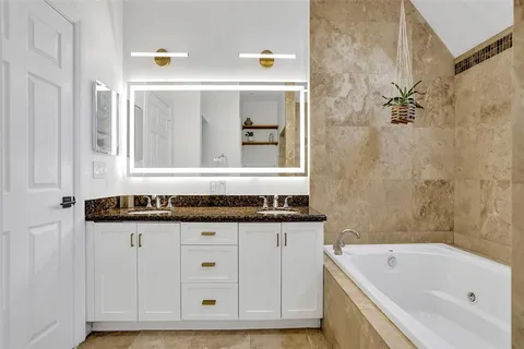 a bathroom with a granite countertop sink and a bathtub