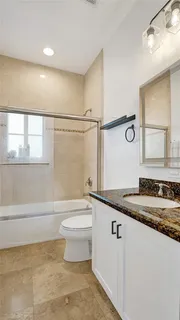 a bathroom with a granite countertop sink a toilet a mirror and bathtub