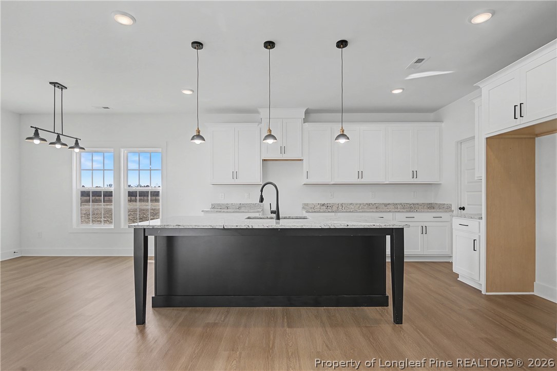 5076 Ross West Road Dunn, NC 28334 - Photo 5 of 8 a kitchen with kitchen island a sink cabinets and wooden floor