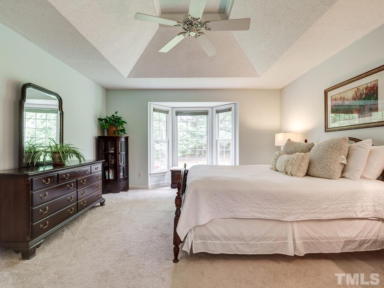 12108 Amoretto Way Raleigh, NC 27613 - Photo 26 of 40 a spacious bedroom with a bed and dresser with mirror