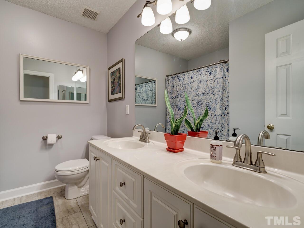 12108 Amoretto Way Raleigh, NC 27613 - Photo 34 of 40 a bathroom with a sink a toilet and a large mirror
