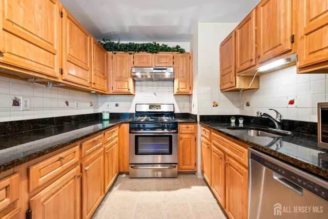 a kitchen with stainless steel appliances granite countertop a sink and a stove