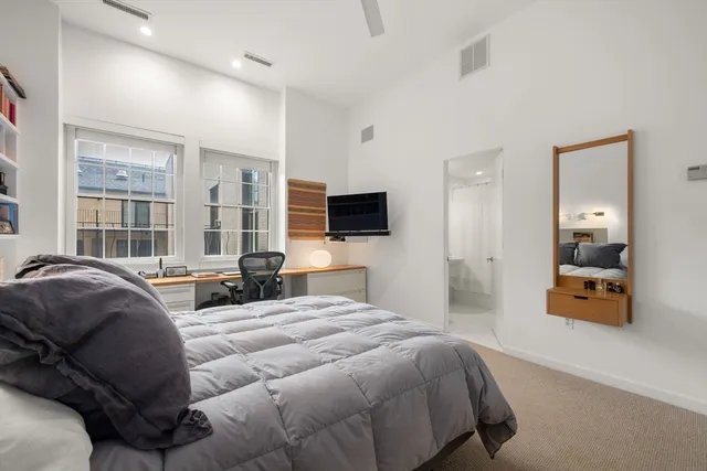 a bedroom with a bed and a flat tv screen on dresser