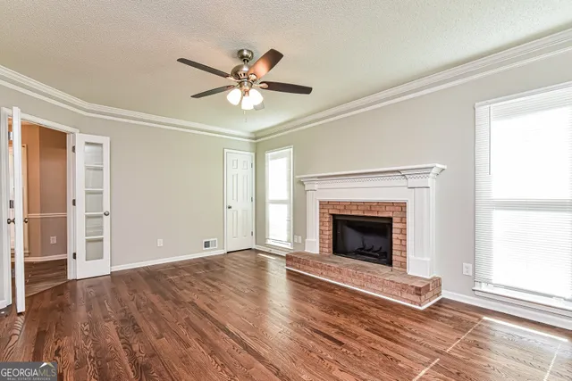 an empty room with wooden floor fireplace and windows
