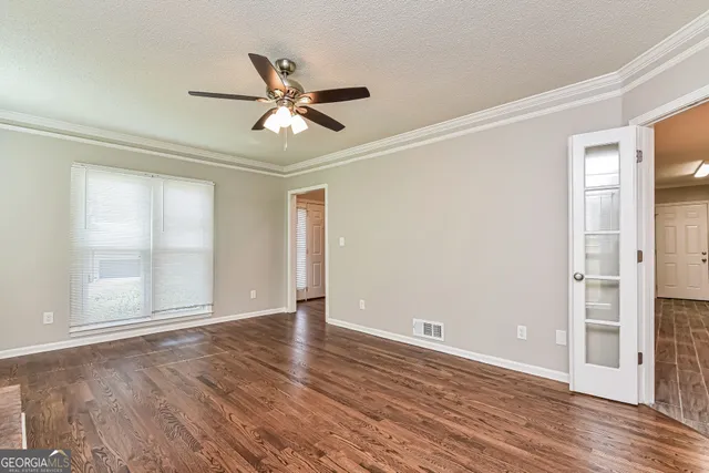 a view of empty room with wooden floor and fan