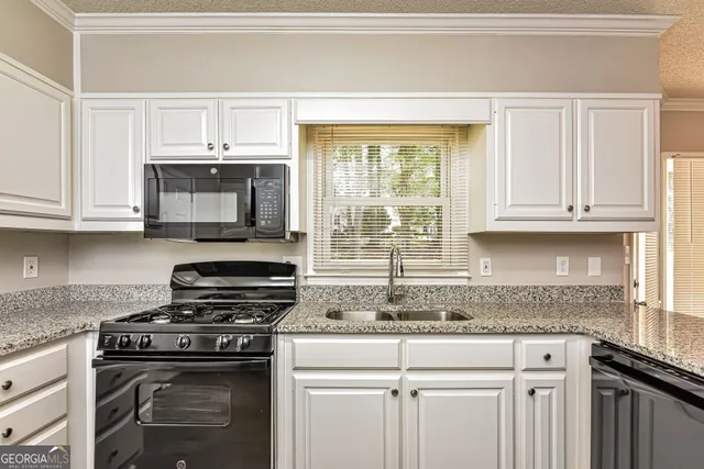 a kitchen with granite countertop a stove top oven microwave and cabinets