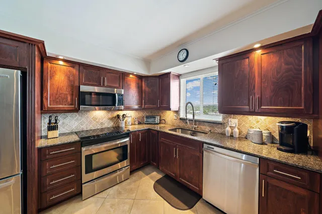 a kitchen with stainless steel appliances granite countertop wooden cabinets a stove a sink and dishwasher