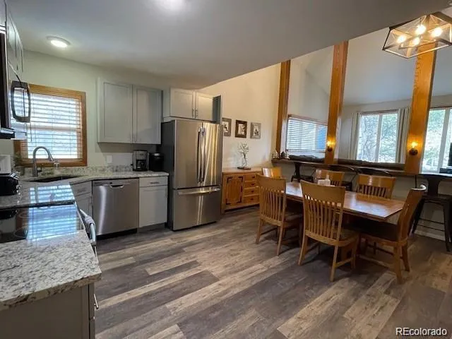 a kitchen with stainless steel appliances granite countertop a table chairs and a refrigerator