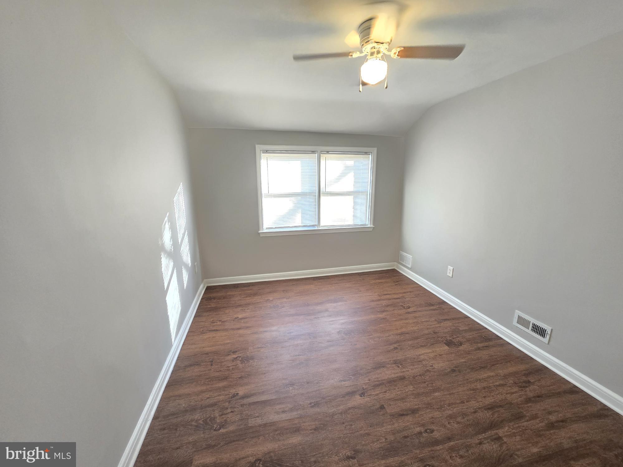 1225 Cochran Avenue Baltimore, MD 21239 - Photo 11 of 22 an empty room with wooden floor fan and windows