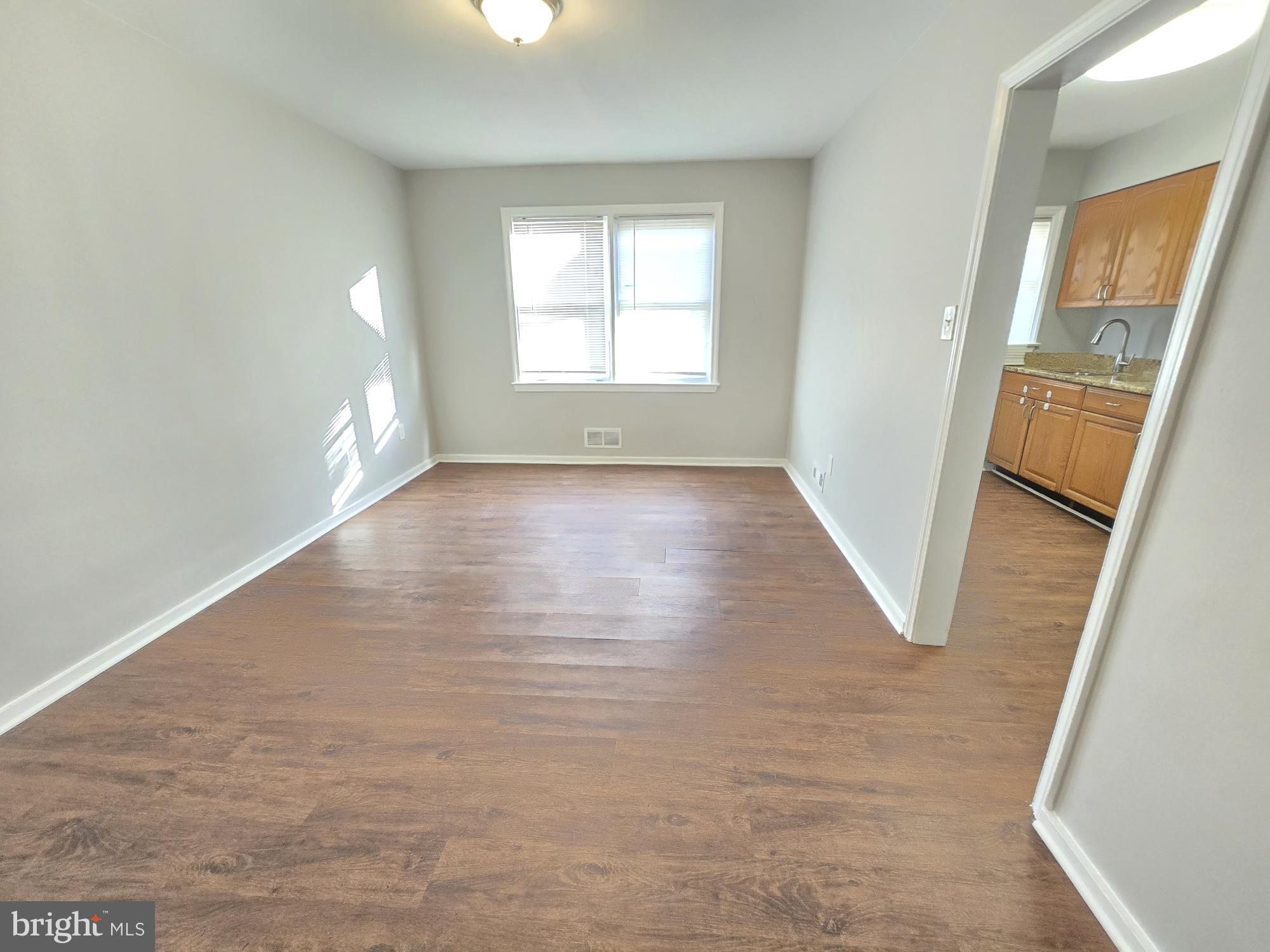 1225 Cochran Avenue Baltimore, MD 21239 - Photo 4 of 22 an empty room with wooden floor and windows