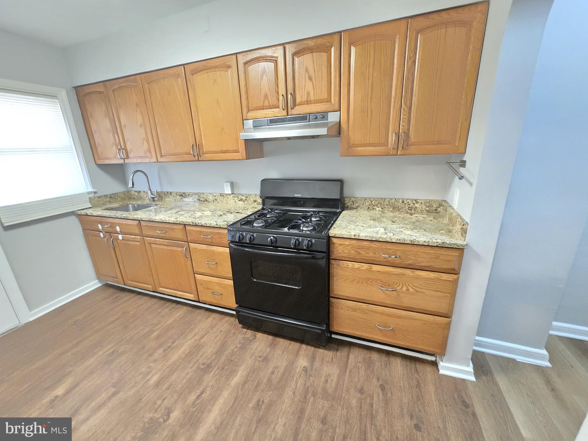 1225 Cochran Avenue Baltimore, MD 21239 - Photo 6 of 22 a kitchen with granite countertop wooden cabinets and a stove