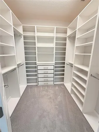 a view of room with walk in closet with empty racks