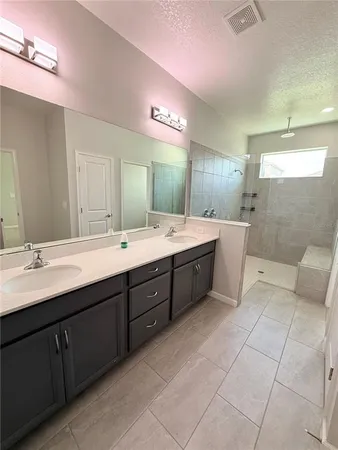 a spacious bathroom with a double vanity sink a mirror and a bathtub