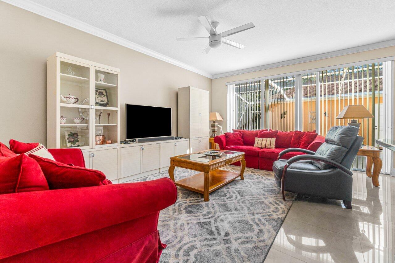 107 Andover Drive Jupiter, FL 33458 - Photo 10 of 26 a living room with furniture a flat screen tv and a floor to ceiling window