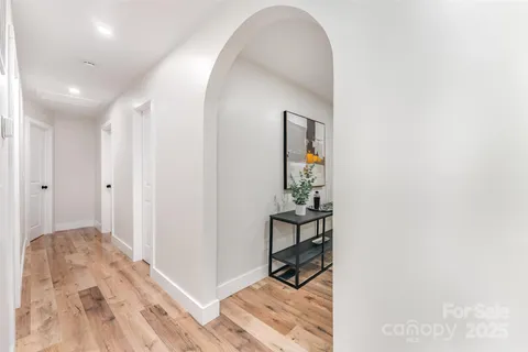 a view of a hallway with wooden floor and a bathroom